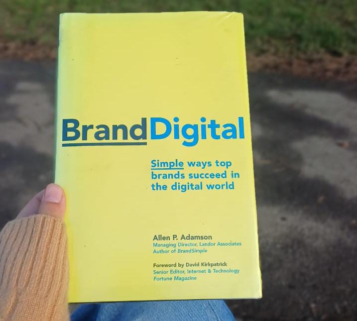 Hand holding the book BrandDigital: Simple Ways Top Brands Succeed in the Digital World by Allen P. Adamson.